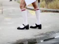 Merceditas negras con calcetines blancos de rejilla y banda roja con logo "DIOR", un look infantil y chic.
