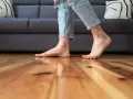 Pies descalzos sobre suelo de madera, sintiendo el frío al caminar cerca del sofá.