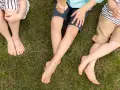 Niños sentados en el césped, uno con shorts talla 28 niño, disfrutando de un helado.