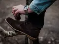 Hombre cepillando bota de cuero marrón, un paso esencial para saber como limpiar botas de cuero y mantenerlas impecables.