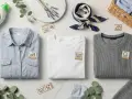 Organiza tu ropa para lavarla: camisa azul, camiseta blanca y suéter gris con símbolos de cuidado. Detergente ecológico y lavanda.