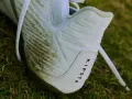 Botines blancos Kipsta con manchas de césped, listos para limpiar.