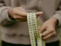 Manos sostienen cinta métrica. La talla 36 UK es un objetivo, pero la cinta muestra medidas en centímetros.