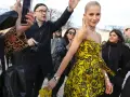 Mujer con un llamativo vestido globo amarillo y negro, rodeada de gente y fotógrafos.