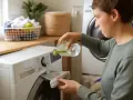 Persona vierte líquido de una botella en el dispensador de la lavadora. El vinagre desinfecta y ayuda a eliminar olores.