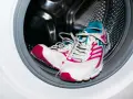 Zapatillas deportivas blancas con detalles fucsia y turquesa listas para aprender como lavar zapatillas en la lavadora.