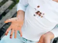Manos y camiseta blanca con manchas de chocolate. Un niño muestra sus manos sucias y su ropa manchada, buscando cómo quitar manchas de chocolate ya lavadas.