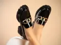 Zapatos negros de charol con cadena dorada, perfectos para aprender como limpiar zapatos de charol y mantener su brillo.