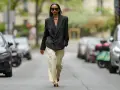 Mujer con blazer negro y pantalones de lino a rayas. Aprende como lavar pantalones de lino para mantenerlos impecables.