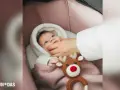 Bebé recién nacido envuelto en manta rosa, con un peluche de reno. Una mano le acaricia la mejilla, como si fuera a poner calcetines a los bebé recién nacido.