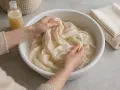 Manos lavando seda en agua con vinagre para un cuidado delicado.