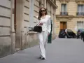 Mujer con un elegante traje blanco, destacando su pantalón ibicenco de corte ancho, camina por una calle parisina.