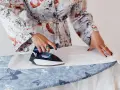 Mujer con bata estampada plancha lino blanco a mano sobre tabla con mariposas.