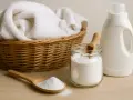 Cesta con ropa blanca, un frasco de bicarbonato y una botella de detergente. ¡Cuidado! el bicarbonato estropea la ropa de color.