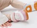 Unas zapatillas de calzado de bebé en tonos blanco, rosa y naranja, listas para los primeros pasos.