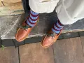 Mocasines de cuero marrón con cordones verdes y calcetines a rayas. Una idea de cómo combinar mocasines mujer para un look casual y chic.