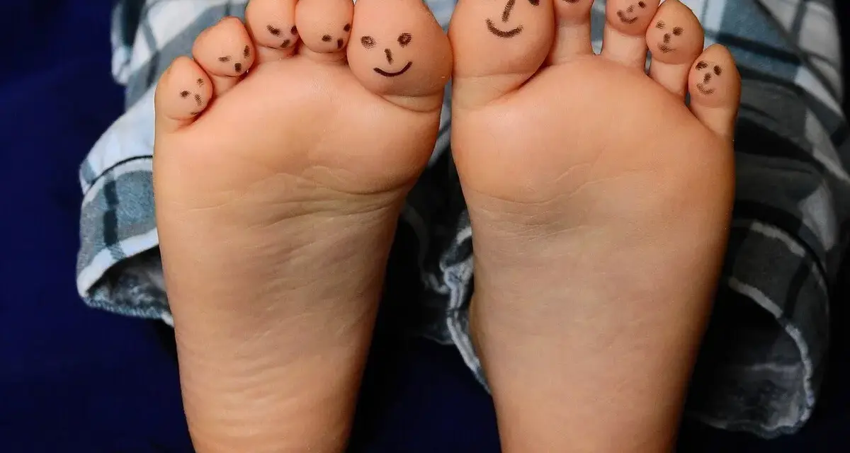 Caritas sonrientes en los dedos de bebés descalzos en invierno, jugando con sus pies.