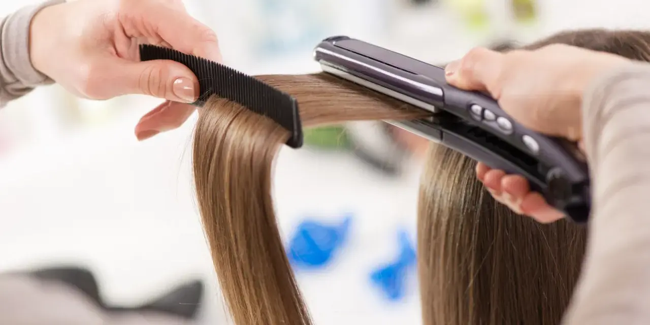 Manos peinando y alisando cabello con una plancha. ¡Sorprendentemente, se puede planchar la ropa con la plancha del pelo!