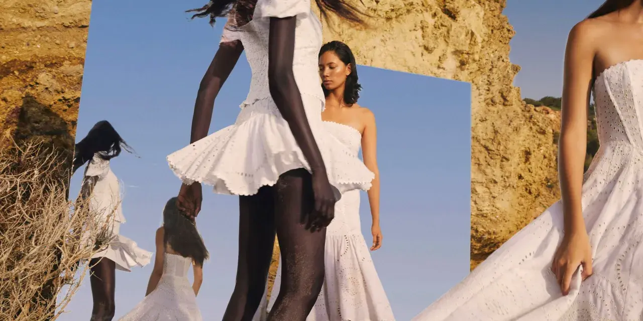 Modelos con vestidos blancos de **Charo Ruiz Ibiza** en un paisaje rocoso, reflejadas en un espejo.