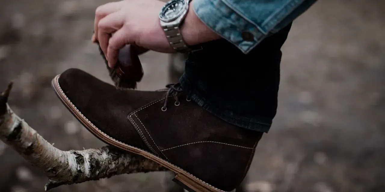 Hombre cepillando bota de cuero marrón, un paso esencial para saber como limpiar botas de cuero y mantenerlas impecables.