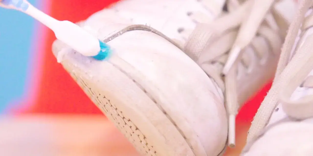 Cepillo dental azul y blanco limpia la suela de unas zapatillas blancas. Un truco para saber como limpiar las suelas de las zapatillas de casa.