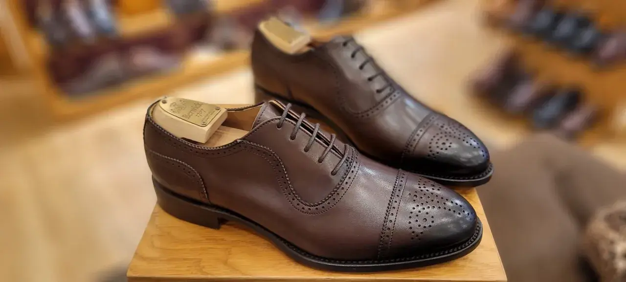Elegantes zapatos de vestir marrones con puntera de cap toe y perforaciones. La talla UK se convierte a EU para un ajuste perfecto.