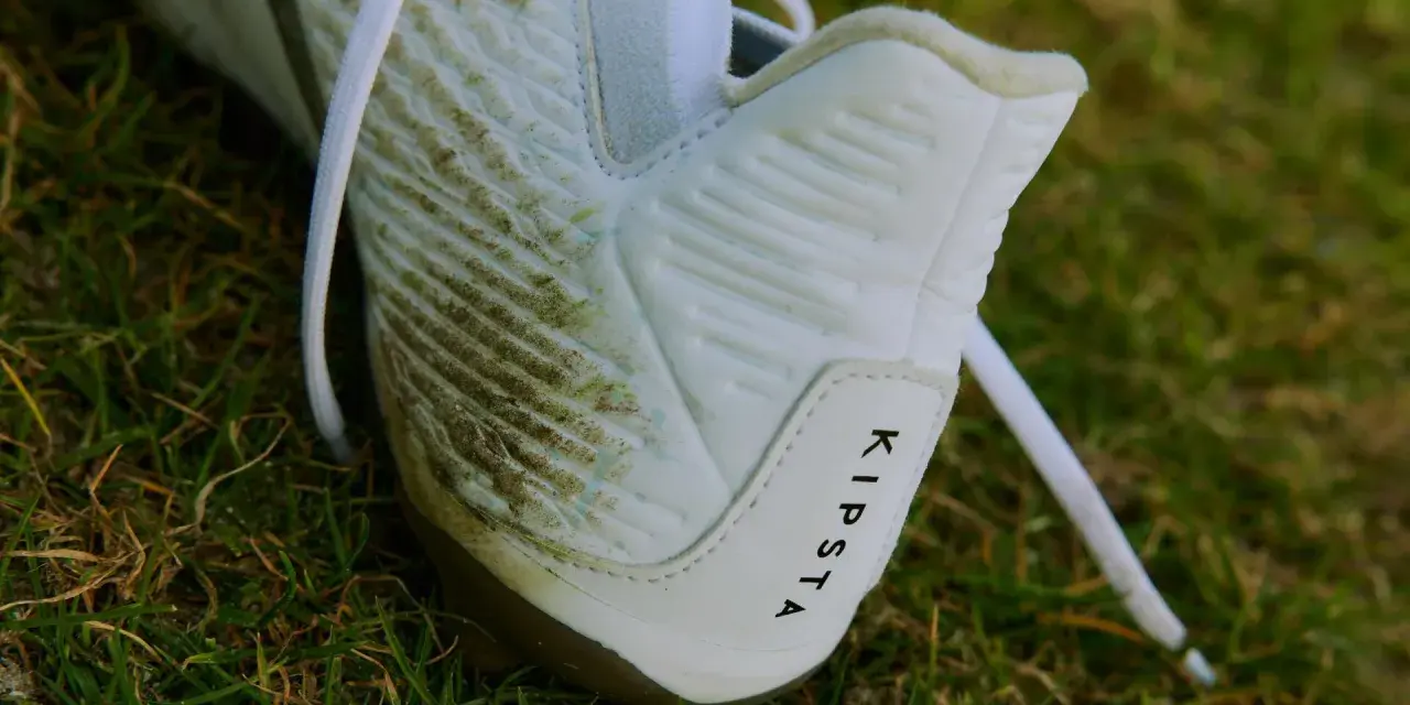 Botines blancos Kipsta con manchas de césped, listos para limpiar.