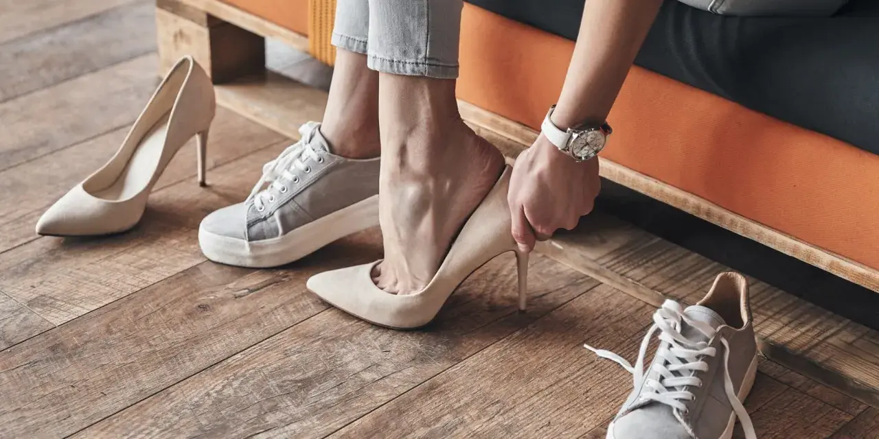 Mujer eligiendo entre varios tipos de pies: zapatillas deportivas y tacones elegantes.