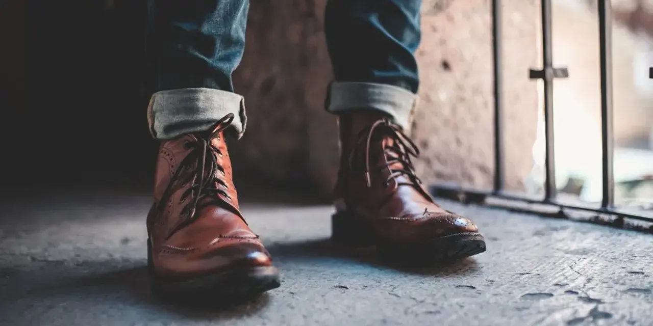 Un outfit con botines hombre: jeans doblados y botines de cuero marrón con cordones, listos para la aventura urbana.