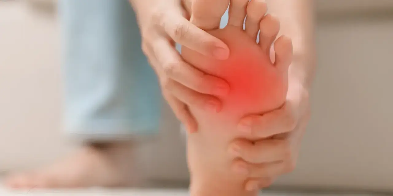 Persona se toca la almohadilla del pie, con una zona roja indicando dolor. Busca remedios caseros para el dolor en la almohadilla del pie.