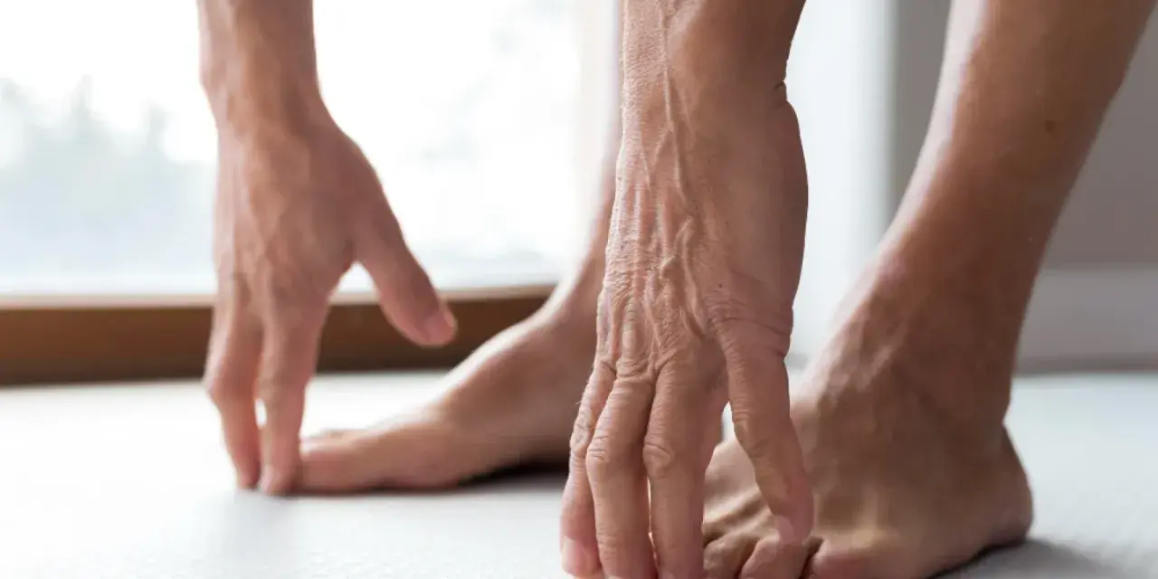 Manos tocando los dedos de los pies, como si sintiera las rampas en los pies.