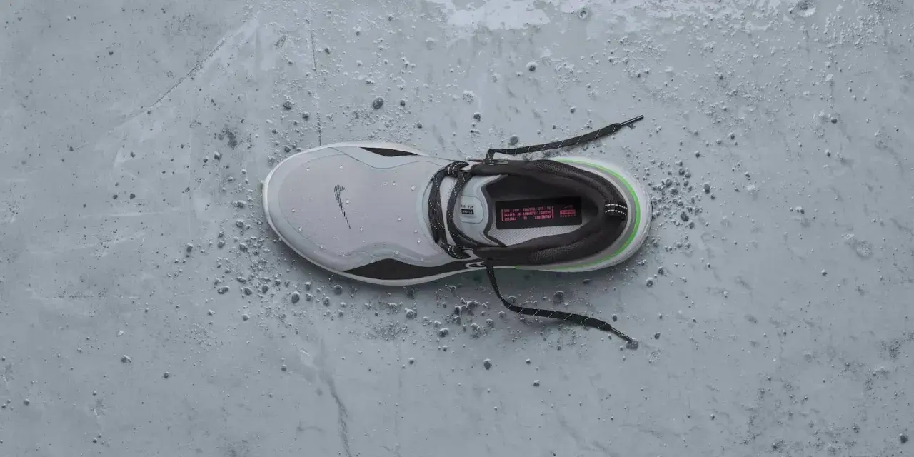 Zapatilla Nike gris con detalles verdes y negros, mojada y con gotas de agua. ¡Perfecta para que se puedan meter las zapatillas en la secadora sin problema!