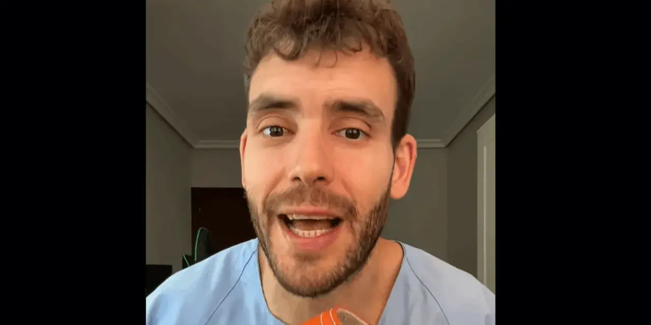 Hombre con bata azul muestra una zapatilla naranja, recordando que los pies crecen con la edad.
