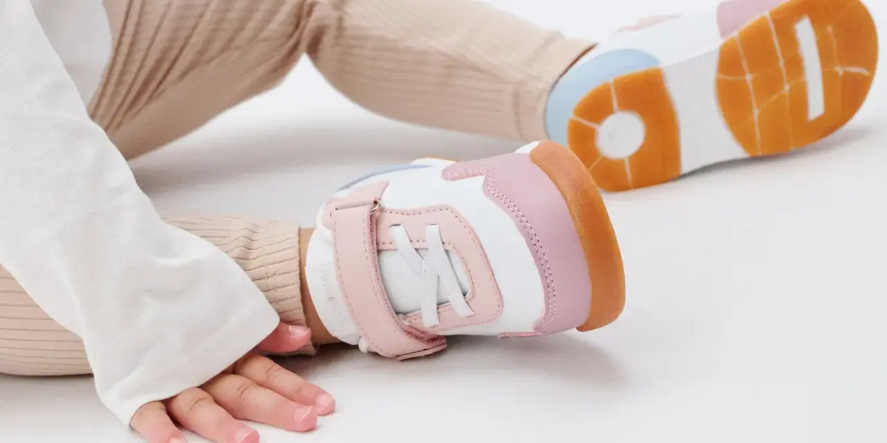 Unas zapatillas de calzado de bebé en tonos blanco, rosa y naranja, listas para los primeros pasos.