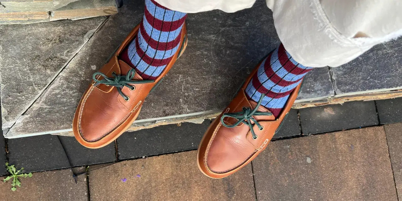 Mocasines de cuero marrón con cordones verdes y calcetines a rayas. Una idea de cómo combinar mocasines mujer para un look casual y chic.