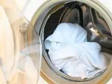 Interior de lavadora con toallas blancas listas para lavar.