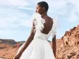 Novia con vestido blanco vaporoso, con volantes en los hombros, ideal para vestidos novia ibiza. Paisaje desértico al atardecer.