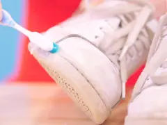 Cepillo dental azul y blanco limpia la suela de unas zapatillas blancas. Un truco para saber como limpiar las suelas de las zapatillas de casa.
