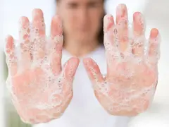 Manos cubiertas de espuma de jabón, un recordatorio de la posible alergia al jabón y la importancia de la higiene.