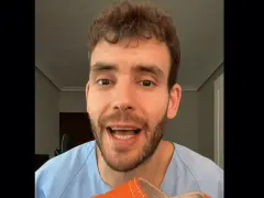 Hombre con bata azul muestra una zapatilla naranja, recordando que los pies crecen con la edad.