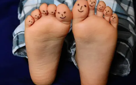 Caritas sonrientes en los dedos de bebés descalzos en invierno, jugando con sus pies.