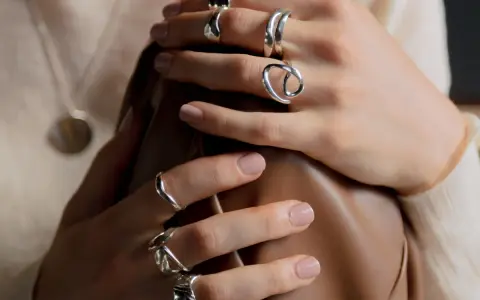 Manos adornadas con varios anillos de plata, uno de ellos con un diseño que recuerda a un anillo de flor.