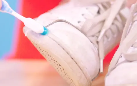 Cepillo dental azul y blanco limpia la suela de unas zapatillas blancas. Un truco para saber como limpiar las suelas de las zapatillas de casa.