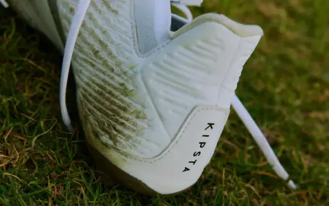 Botines blancos Kipsta con manchas de césped, listos para limpiar.
