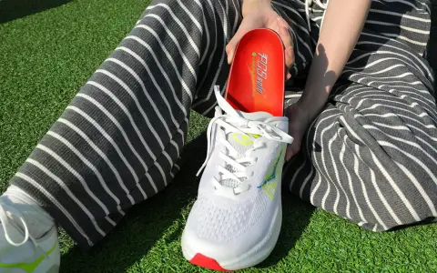 Persona muestra una plantilla roja para el arco plantar, lista para ser colocada en un zapato deportivo blanco.