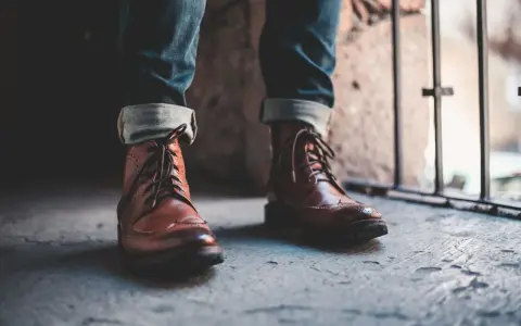 Un outfit con botines hombre: jeans doblados y botines de cuero marrón con cordones, listos para la aventura urbana.