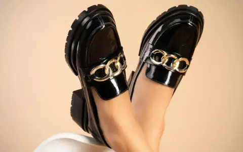 Zapatos negros de charol con cadena dorada, perfectos para aprender como limpiar zapatos de charol y mantener su brillo.