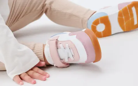 Unas zapatillas de calzado de bebé en tonos blanco, rosa y naranja, listas para los primeros pasos.
