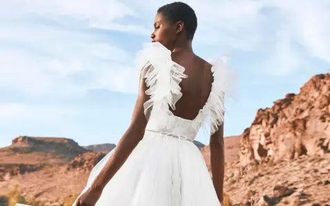 Novia con vestido blanco vaporoso, con volantes en los hombros, ideal para vestidos novia ibiza. Paisaje desértico al atardecer.