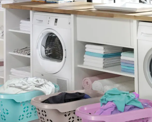 Lavandería moderna con lavadora y secadora. Cestas con ropa sucia y toallas dobladas, evocando la eficiencia de los detergentes años 60.